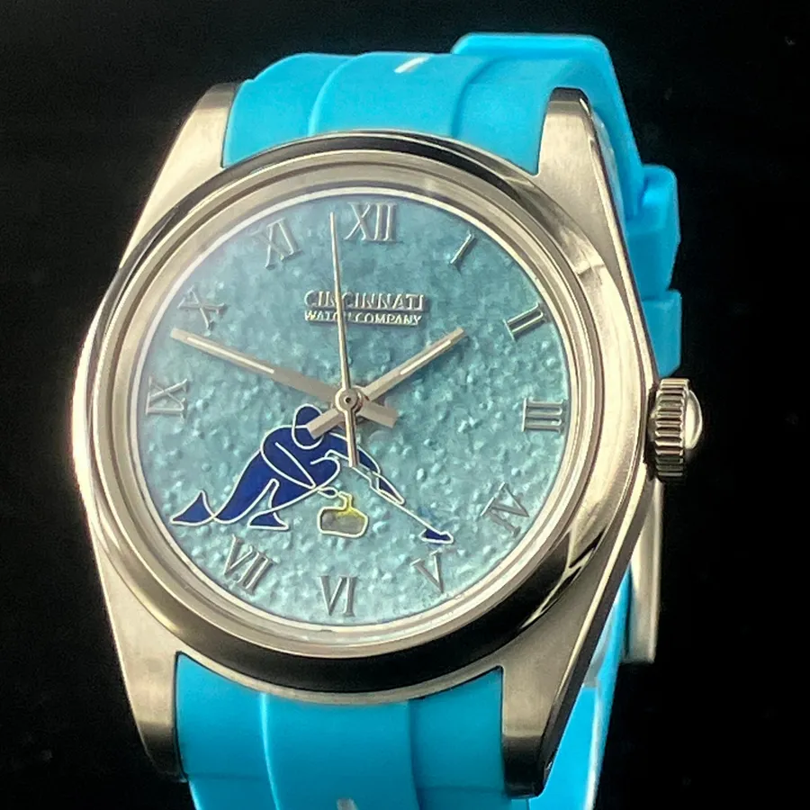 Cincinnati Watch Company Curling, ice-blue pebbled enamel dial with the 2026 Olympic curling pictogram, on a light blue silicone strap