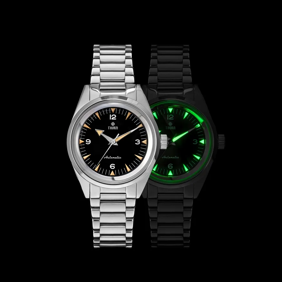 Thorn T026A Railmaster-style watch with black dial, smooth steel bezel and steel bracelet, beside a lume shot