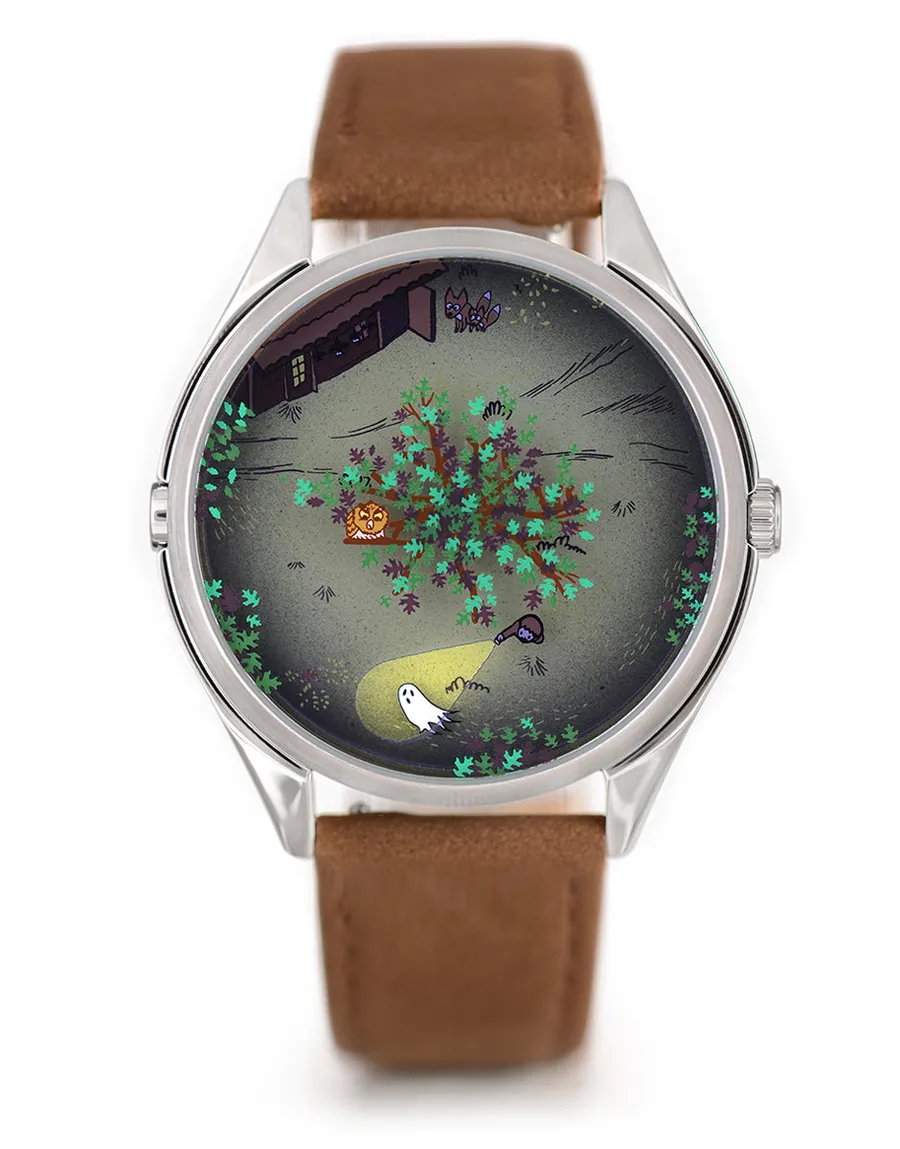 Mr Jones Night Howl, grey night-forest dial seen from above with a tree, a ghost and a torch beam, steel case on brown suede, front view