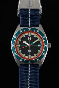 Pook Raja II with black dial, red-orange chapter ring, date at 3 and teal dive bezel on a navy paranato strap