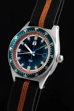Pook Raja with dark dial, orange-and-white chapter ring, date at 3 and teal dive bezel on a black-and-orange paranato strap