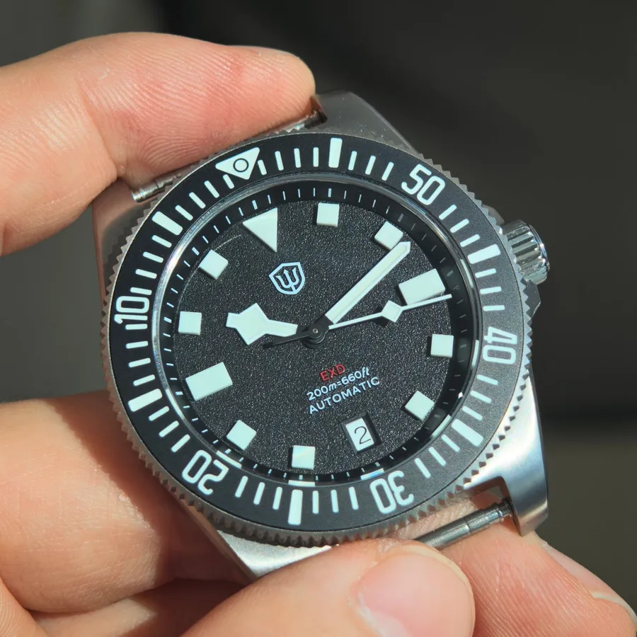 Watchdives EXD-40 automatic with black date dial, held in hand